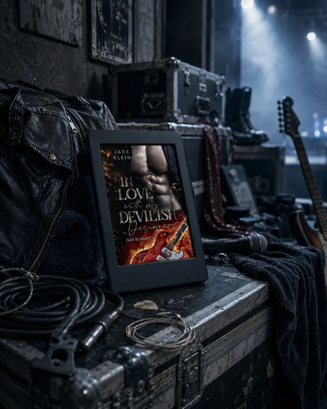 Kindle-Mockup des Covers von »In Love with my devilish Designer«, umgeben von Kabeln, Plektren und Gitarrensaiten auf einer Flightcase backstage.