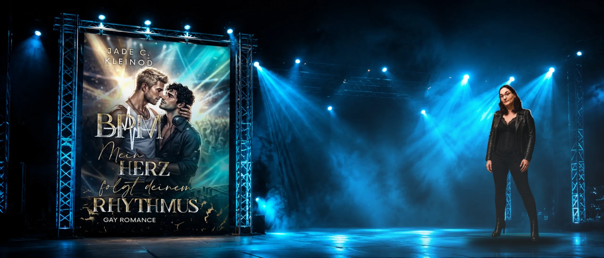 Autorin Jade C. Kleinod steht auf einer blau beleuchteten Konzertbühne neben dem großformatigen Cover ihres Gay-Romance-Romans »BPM - Mein Herz folgt deinem Rhythmus«, mit dem Hinweis auf den Erscheinungstermin am 23.08.2026.